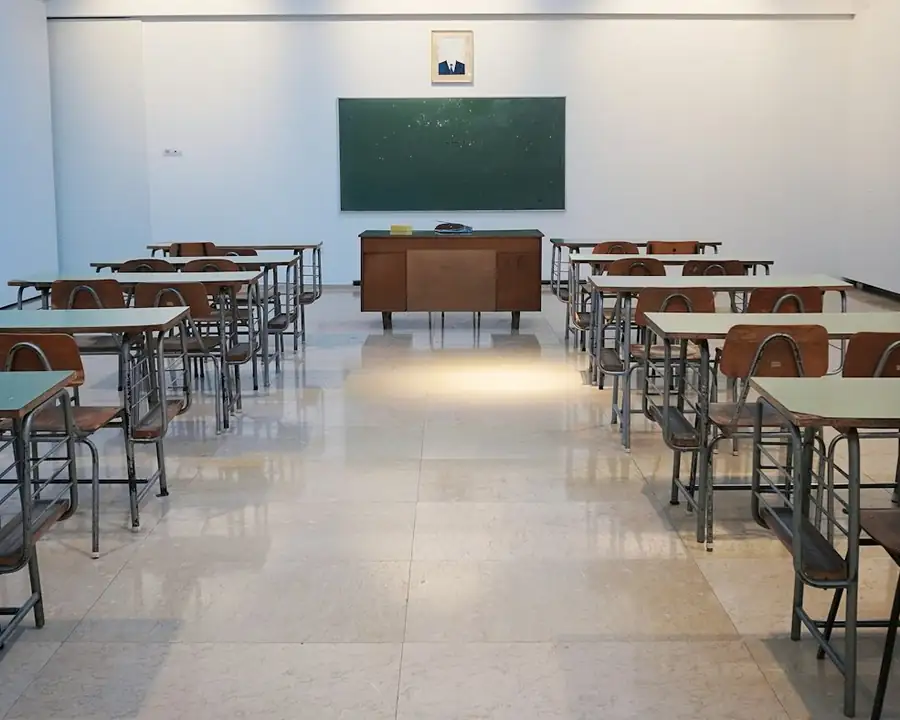 An empty classroom with rows of desks and a chalkboard